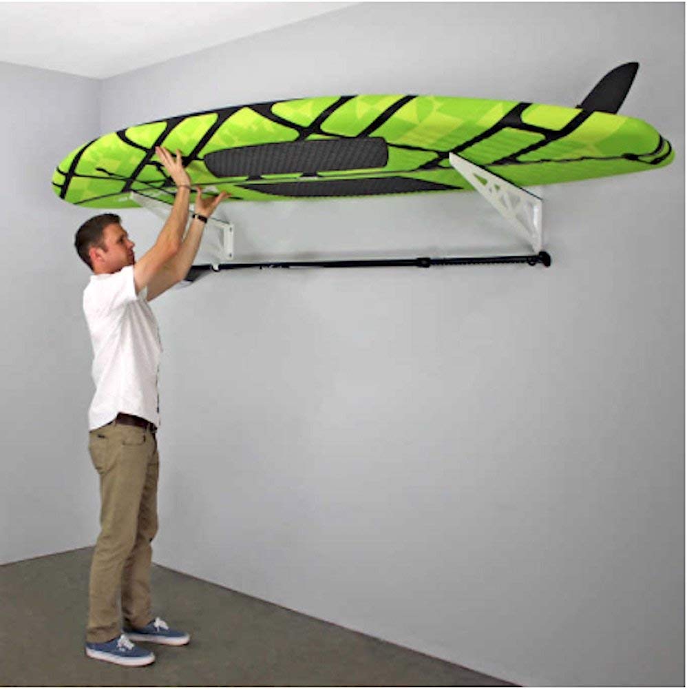 person removing a paddle board from paddle board rack